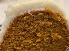 a slice of carrot cake with white frosting on a blue and white plate next to a fork