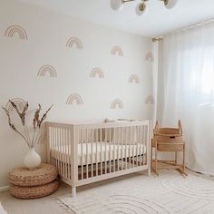 a baby's room with a white crib and rainbow wallpaper