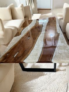 a table made out of wood and glass in a living room with white couches