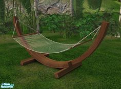 a wooden hammock in the middle of a lush green field with palm trees