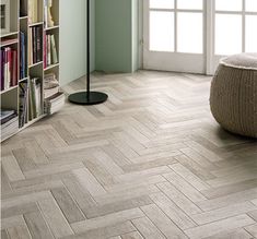 a living room with wood flooring and bookshelves in the corner, along with a round ottoman