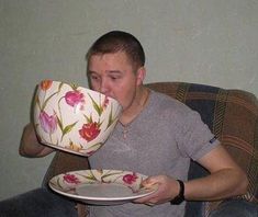 a man sitting in a chair drinking out of a teacup and holding a plate