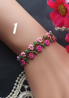 a close up of a person's arm wearing a bracelet with flowers on it