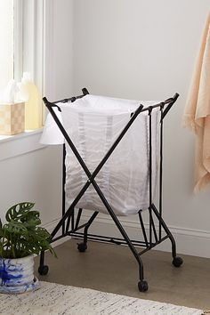 an ironing board next to a potted plant on the floor in front of a window