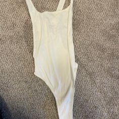 a white one piece swimsuit laying on top of a carpeted floor next to a pair of shoes