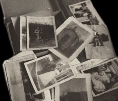 black and white photograph of old photos on the floor in an open suitcase with papers all over it