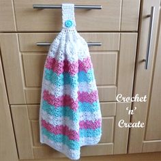 a crocheted towel hanging from a hook on a cabinet in a kitchen with wooden cabinets