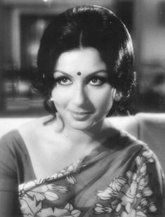 an old black and white photo of a woman wearing a sari with flowers on it