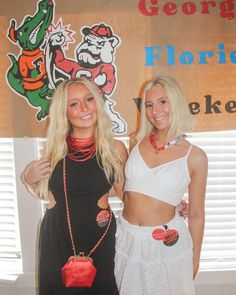 two beautiful young women standing next to each other in front of a wall with a sign