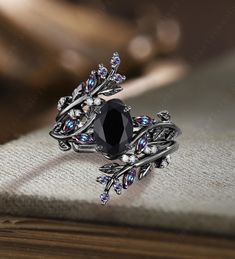 a black diamond ring sitting on top of a wooden table next to an open book