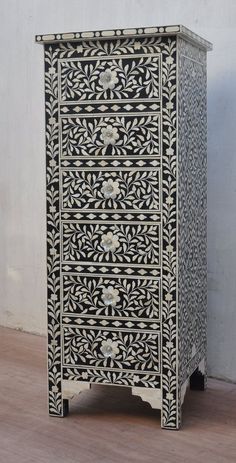 an ornate black and white chest of drawers