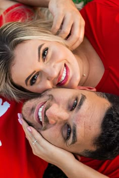 a man and woman laying on the ground smiling at the camera with their arms around each other