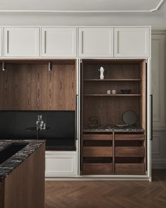 an empty kitchen with wooden cabinets and marble counter tops, along with dark wood flooring