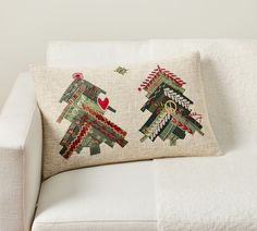 a white couch with two christmas trees on it's back and a red heart in the middle