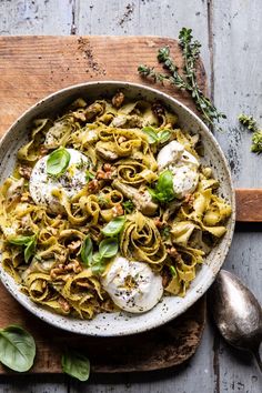 a bowl filled with pasta and meat on top of a wooden cutting board next to two spoons