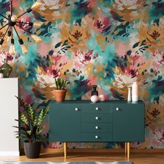 a floral wallpaper design with green cabinet and potted plants on the sideboard