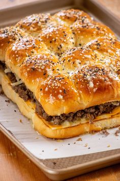 a sandwich with cheese and meat is on a baking tray, ready to be eaten