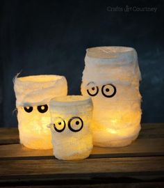 three mason jars with eyes on them sitting on a table