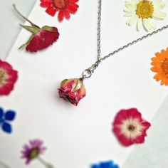 This Pink Rose necklace is a beautiful and unique piece of jewellery that features a real pink rose covered in resin. As a symbol of femininity, grace, and fresh love, this necklace is the perfect gift for a loved one on special occasions like Birthdays and Valentine's Day. The dried flower pendant is around 2 cm in size and hangs from a stylish silver chain that measures approximately 21 cm in length. Please note that as each piece is unique, the size may vary slightly due to natural variations Delicate Rose Necklace With Roses Detail, Pink Flower Jewelry With Rose Design, Delicate Pink Flower Pendant Necklace, Delicate Pink Pendant Flower Necklace, Pink Flower Pendant Necklace For Valentine's Day, Valentine's Day Pink Flower Pendant Necklace, Delicate Pink Flower Necklace For Gift, Dainty Flower-shaped Rose Jewelry, Dainty Rose Flower Jewelry