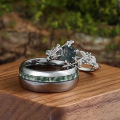 two wedding rings sitting on top of a wooden table next to each other with green and white designs