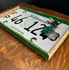 a green and white license plate sitting on top of a wooden table next to a pair of scissors