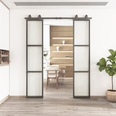 an open door leading to a dining room with white walls and wood flooring, along with a potted plant