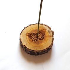 a wooden slice with a butterfly on it and a green twig sticking out of it