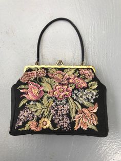 Black mini handbag with tapestry floral design on the front. Edges and clasp in gold satin lustre. Small black fabric handle. A stylish item for a night out or other occasion. A great gift for yourself or a close friend. Materials: no labels, front part is tapestry. MEASUREMENTS -  Length: 7.67 inches / 19.5 cm Height: 6.10 inches / 15.5 cm Depth: 1.18 inches / 3 cm CONDITION: Very good vintage condition. All measurements are taken with the garment lying flat. Due to lighting, the color of the p Elegant Embroidered Top Handle Satchel, Elegant Satchel Shoulder Bag With Floral Embroidery, Elegant Floral Embroidered Satchel Shoulder Bag, Vintage Evening Bag In Tapestry Material, Vintage Tapestry Bag For Evening, Vintage Rectangular Bags With Gold Embroidery, Elegant Bag With Top Handle And Floral Embroidery, Elegant Tote Bag With Floral Embroidery, Elegant Top Handle Bag With Floral Embroidery