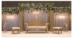 an elaborately decorated stage set with white flowers and greenery on the back wall