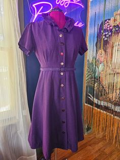 Purple and pink dress, likely from the 50's or 60's.  Belted with  buttons all the way down and 2 snap closures (one at neck and one at waist).  Material feels like a heavy polyester/cotton blend.  Main coloration is purple with pink highlights throughout.  There are spots where the pink is more prominent, and these appear to be inherent to the material.  Some pictures have zoomed in on these spots.   The fit is exquisite and will flatter your figure highly! Measurements taken while garment is laying flat: Sleeve (seam to end) - 7" Chest - 18" Waist - 14.5" Back of gown (nape to hem) - 35.5" Vintage sizes are different than modern sizing, so please review the measurements listed, double them, and measure your body to ensure a decent fit. Please note, items in my shop are vintage and pre-ow Dress With Waist Belt, Dark Purple Dress, Dark Purple Dresses, Purple Vintage, Pink Highlights, New Braunfels, 50s Dresses, Vintage Belts, Audrey Hepburn