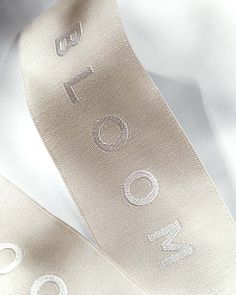 two satin ribbons with the word love written on them, one is white and the other is gold