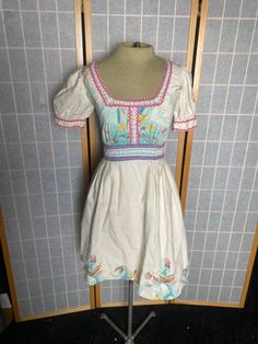 "Vintage 1970's cottage core cute puffy sleeves summer dress with ric rac and lace trim. Flower prints on hem and bodice. Extra small In great vintage condition. Women's size xs 34\" bust 24\" waist free hips up to 46\" 13.5\" shoulder to waist 22.75\" waist to hem" Cute Square Neck Puff Sleeve Dress For Garden Party, Cute Fitted Puff Sleeve Dress With Smocked Bodice, Puff Sleeve Dress With Lace Trim For Garden Party, Spring Garden Party Puff Sleeve Dress With Empire Waist, Summer Prairie Dress With Puff Sleeves And Ruffles, Summer Puff Sleeve Dress With Empire Waist, Spring Vintage A-line Cotton Dress, Spring Vintage Fitted Cotton Dress, Spring Vintage Cotton Fitted Dress