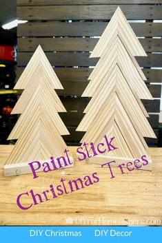 some wooden christmas trees on a table with text overlay that says paint stick christmas trees