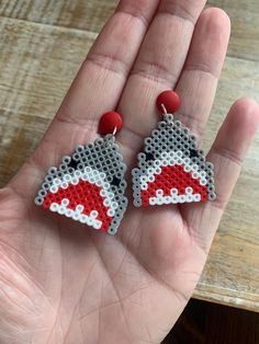 a pair of red and gray earrings on a person's hand