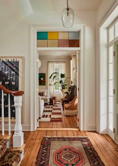 a hallway with wooden floors and colorful rugs on the floor next to an open door