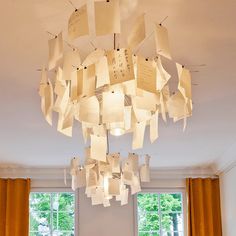 a chandelier made out of sheets of paper hanging from the ceiling in a living room