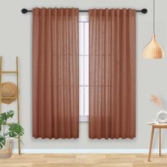 a living room with brown curtains and a wooden table in front of a window that has a potted plant next to it