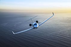 an airplane flying over the ocean at sunset