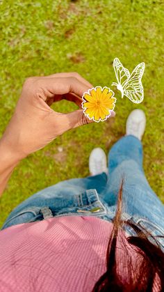 a person holding a yellow flower with two butterflies on top of their head in the grass