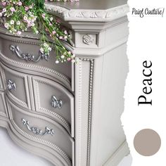 a dresser with flowers on top and the words peace painted in white lettering above it