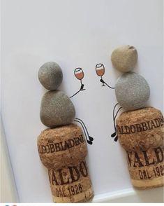 two wine glasses sitting on top of rocks in front of a sign that says,