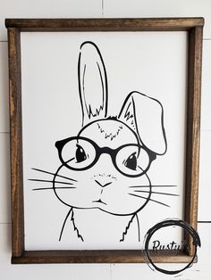 a black and white drawing of a rabbit with glasses on it's face in a wooden frame