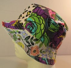 a white mannequin head wearing a multicolored hat with flowers on it