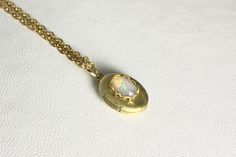 This sweet, small, OVAL brass locket has a natural Ethiopian Opal cabochon set on the front.  The cabochon sits in a brass lace edged setting. It hangs on a 16" gold-plated stainless-steel chain necklace.  The locket is approximately 11x16mm.  The cabochon is 5x7mm.  Arrives in an eco-friendly jewelry box, ready for gifting. MORE lockets in the shop! FREE SHIPPING! THANK YOU FOR VISITING! Oval Cabochon Brass Necklace, Victorian Oval Cabochon Necklace Gift, Handmade Oval Brass Locket Necklace, Handmade Gold Locket Necklace For Memorial, Stainless Steel Chain Necklace, Eco Friendly Jewelry, Lace Edging, Locket Necklace, Steel Chain