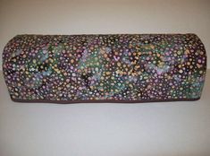 a roll of toilet paper covered in multicolored polka dot pattern on a white surface