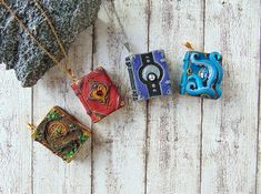 four different colored pendants sitting on top of a white wooden table next to a rock