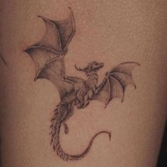 a dragon tattoo on the back of a woman's thigh is shown in black and white