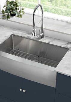 a stainless steel sink in a kitchen with marble counter tops and blue cabinets around it