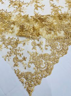 gold embroidered lace on white table cloth with golden flowers and leaves in the center, closeup