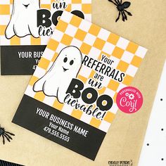 two halloween business cards on top of a table with black and yellow checkered paper